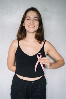 手持粉红丝带的女人微笑着宣传乳腺癌意识