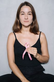 年轻女子手持粉红丝带符号，在宁静的肖像中提高乳腺癌意识