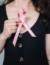 一名妇女手持粉红丝带，象征着乳腺癌防治意识，倡导健康理念