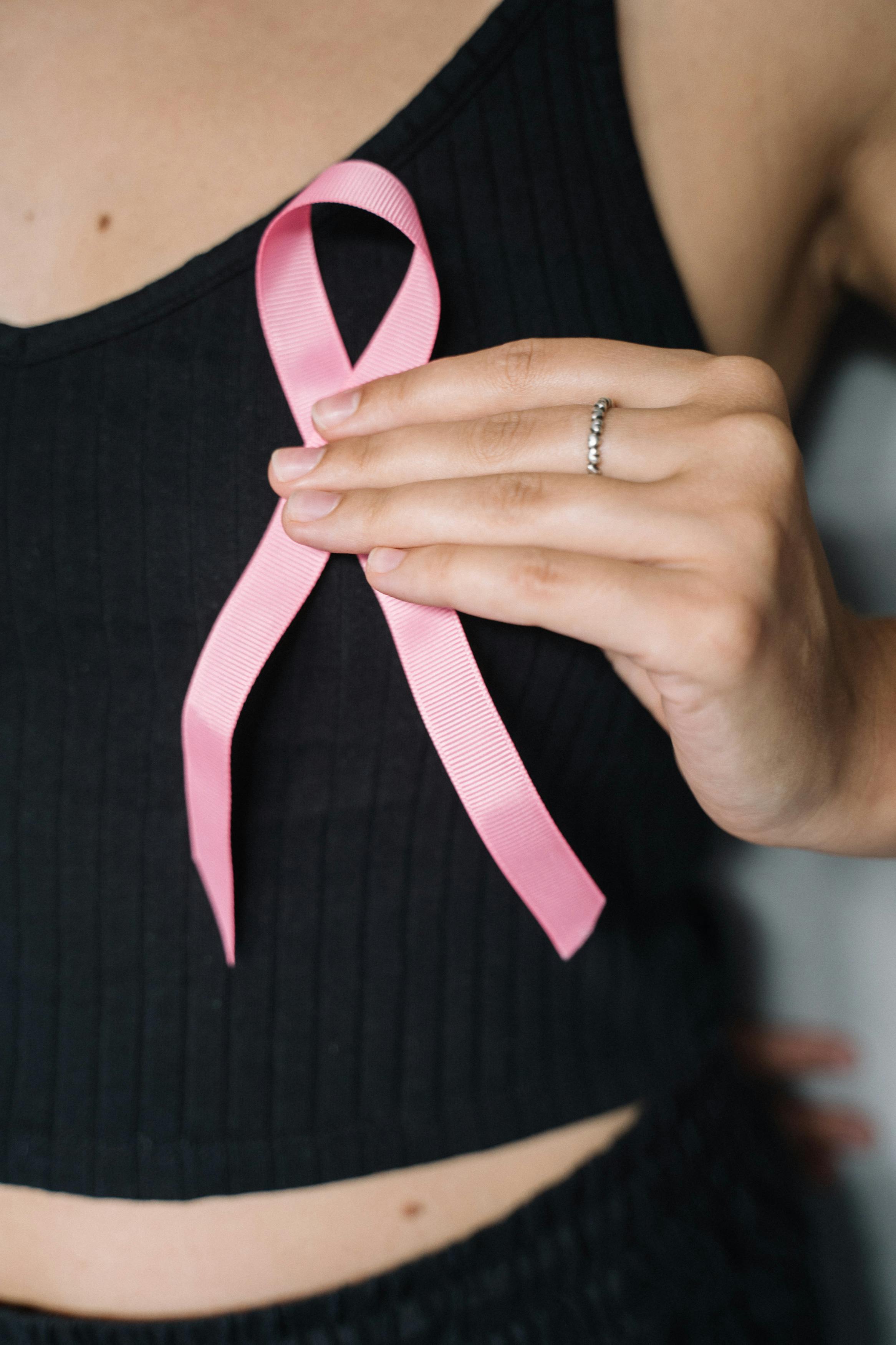 woman in black tank top holding pink ribbon