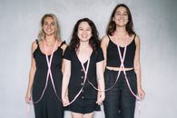 三位微笑的女性手牵粉红丝带，为乳腺癌的认知与支持助力