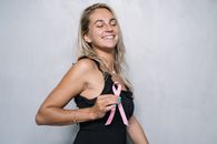 一位快乐的女性闭着眼睛，手拿一条象征乳腺癌意识的粉红色丝带