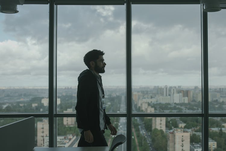 Man Walking Along Office Windows Overlooking The City