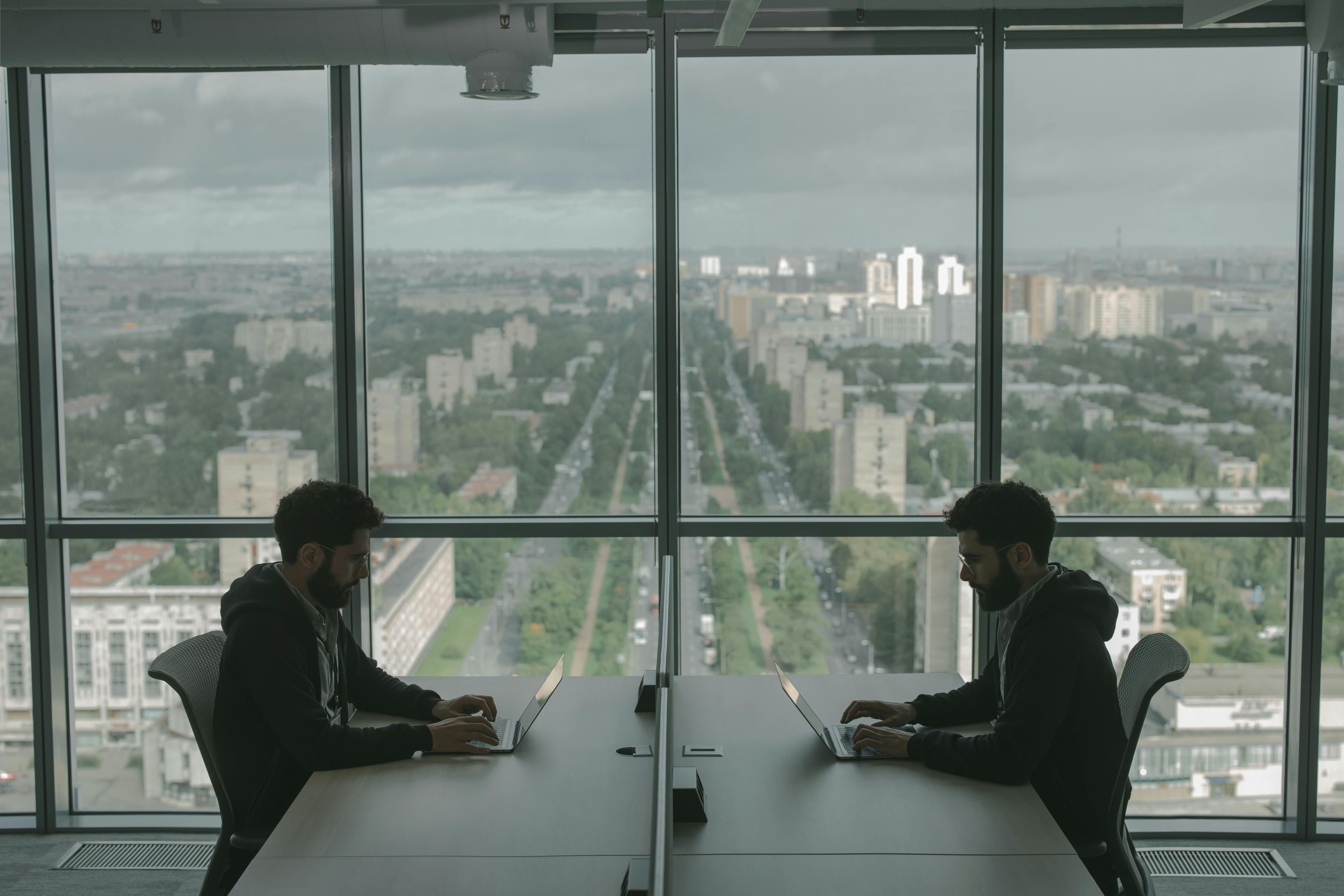 Man sitting beside glass window near high rise building photo