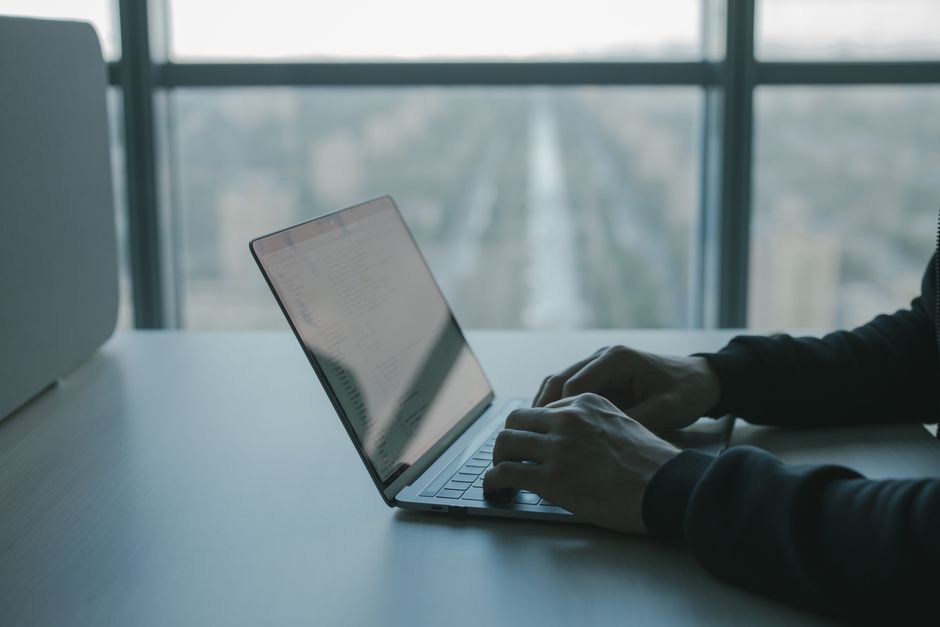 A person typing on a laptop in an office setting, focused on work.