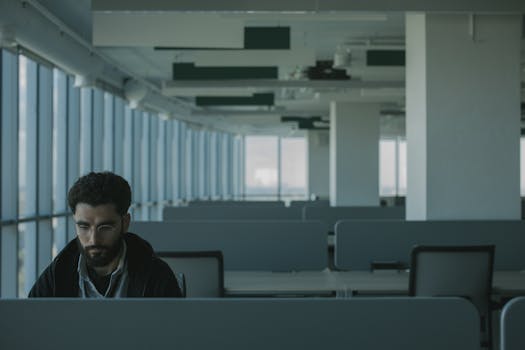 Bearded man working alone in a modern office space, emphasizing solitude.