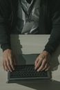 一张在办公环境中，一个人头顶上方拍摄的、他正在办公桌前用笔记本电脑打字的照片