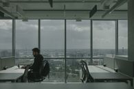 在现代办公室里用笔记本电脑工作的人，可以看到广阔的城市景观
