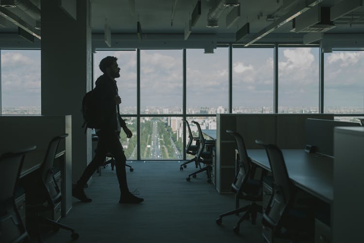 A Man In Black Jacket Walking Inside An Office