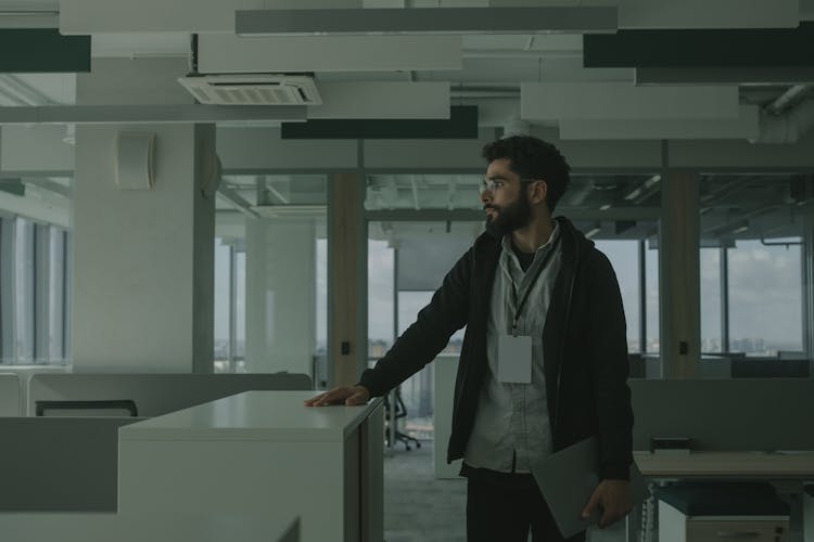 A Standing Man In Black Jacket Holding A Laptop