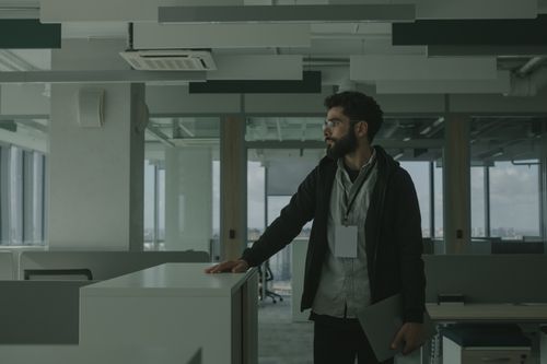 Free Business professional in a modern office with smart attire and a laptop, gazing thoughtfully. Stock Photo