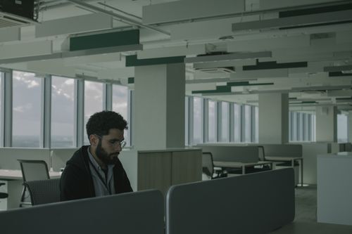 Free Man in eyeglasses working alone in a spacious modern office with large windows. Stock Photo