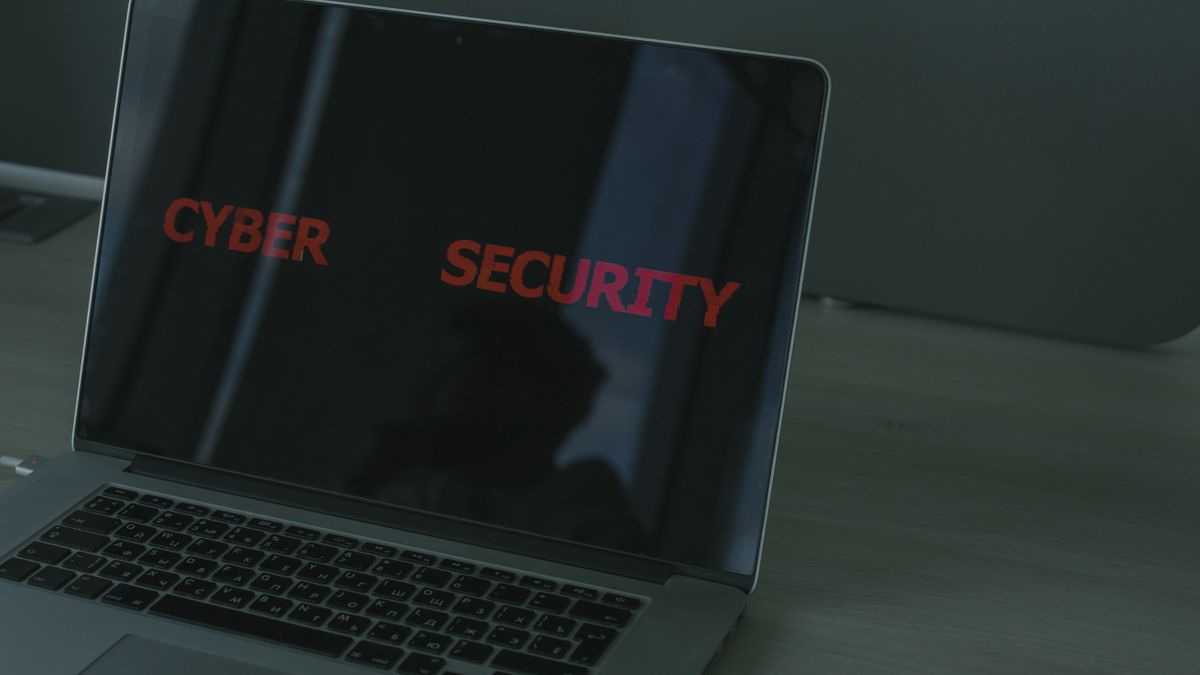 Notebook aberto sobre mesa de trabalho com tela exibindo códigos, representando segurança digital no home office