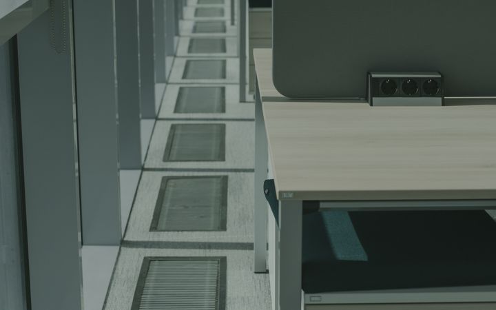 Sunlit modern office workspace with desks and partitions view.