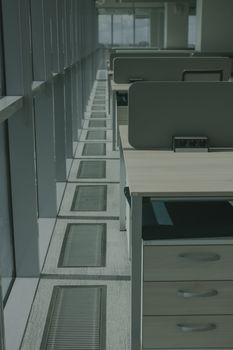Sunlit modern office workspace with desks and partitions view.