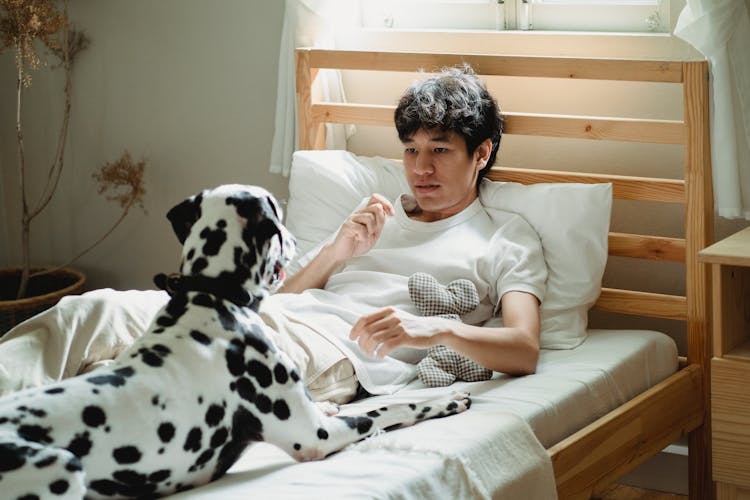 A Man Lying On The Bed With His Dog