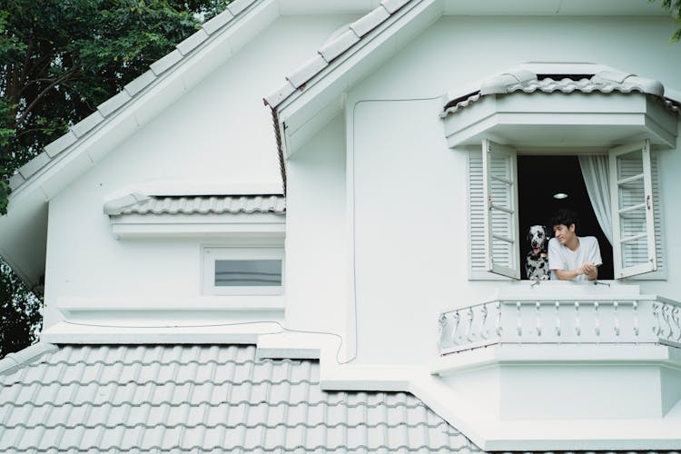 Man And Dog Looking Out House Window