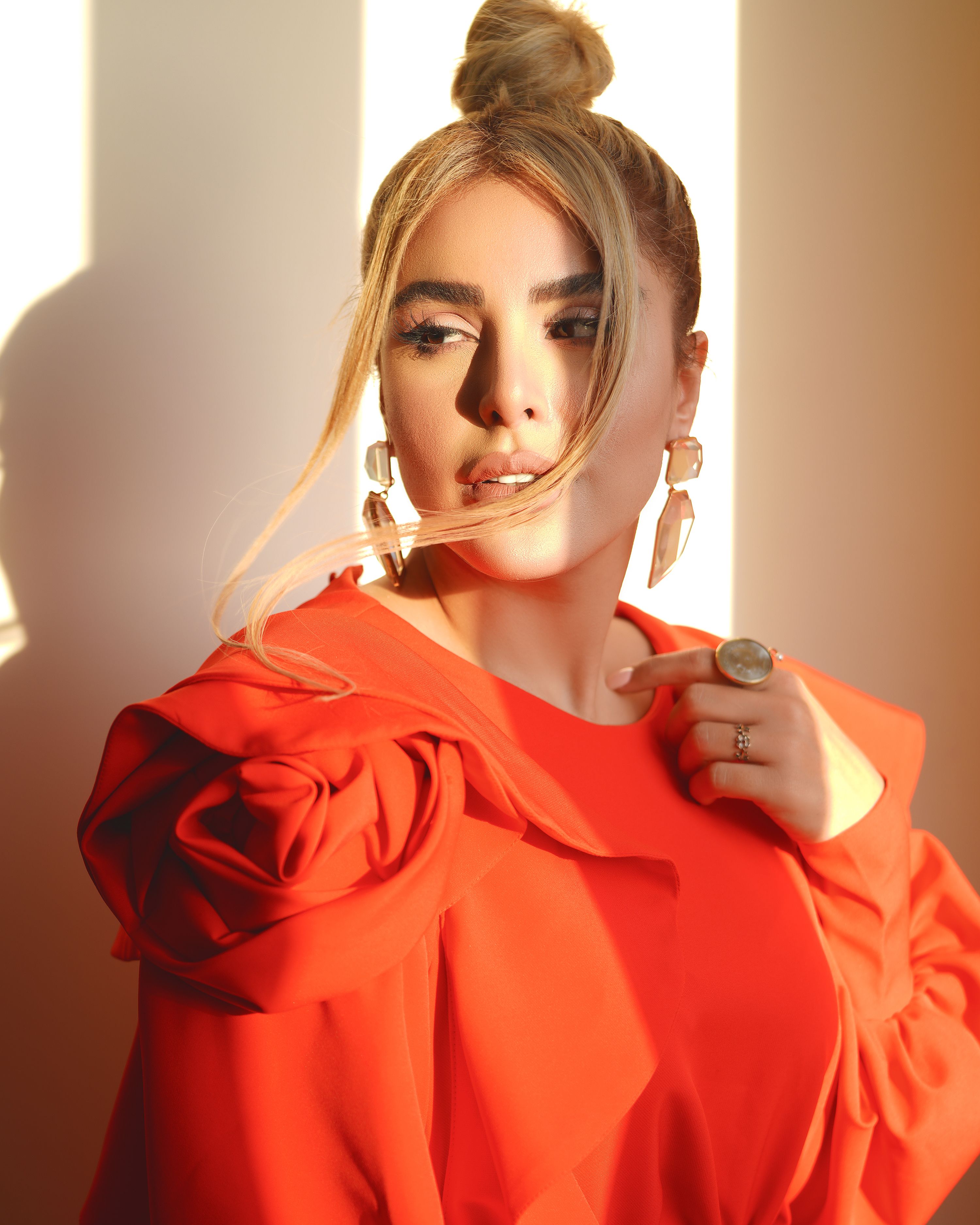 Portrait of a stylish woman in a red dress with a hair bun, exuding elegance.
