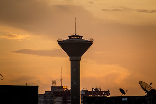 Silhouette of a water tower against a vibrant Brazilian sunset, highlighting urban infrastructure.