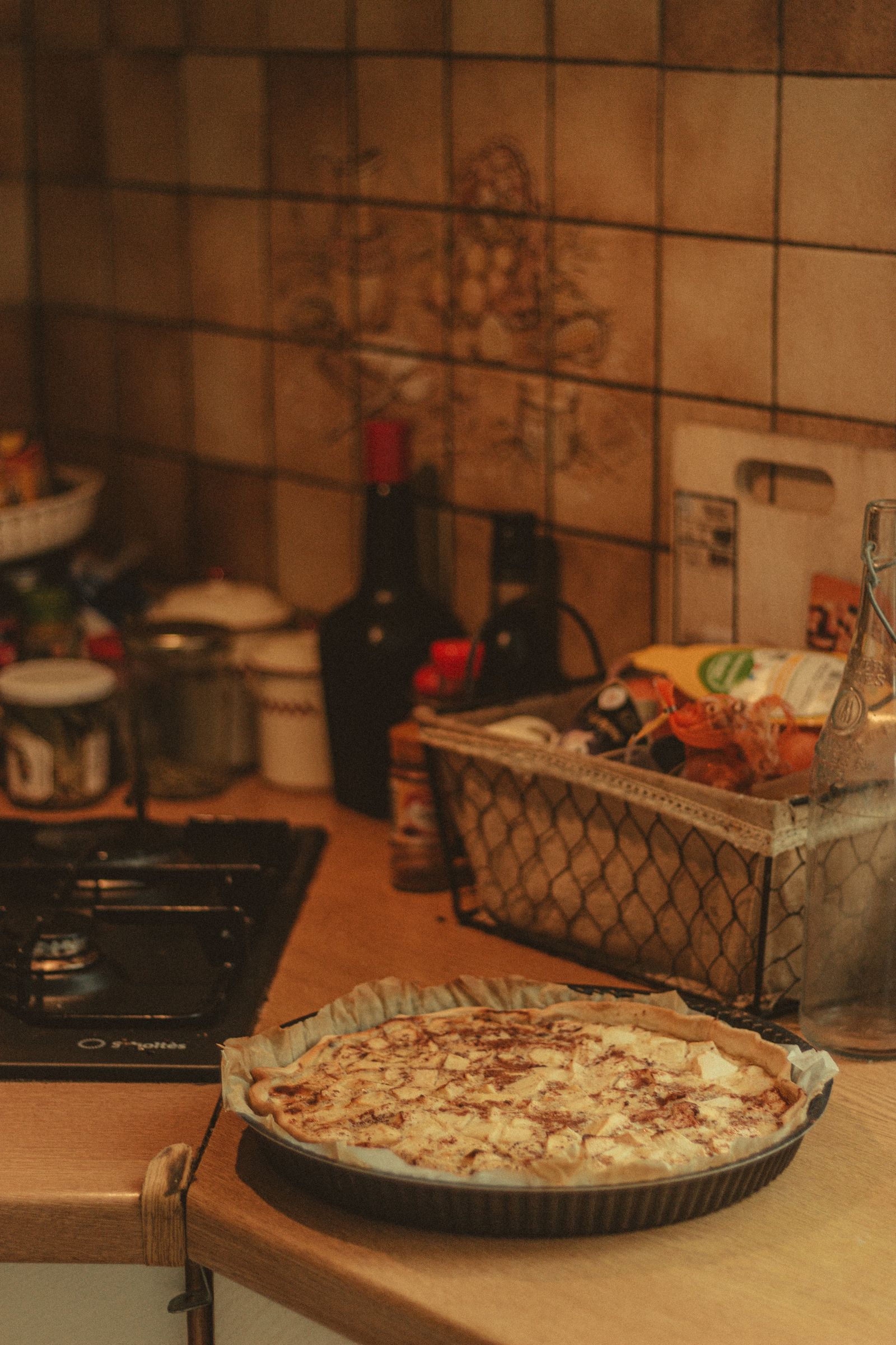 High angle of fresh baked pie with apple placed on kitchen table near seasonings and stove