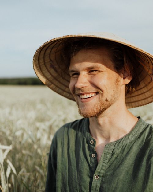 Free Portrait of a smiling farmer in a sunlit wheat field wearing a straw hat. Stock Photo