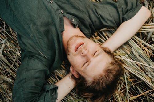 Man in Black Button Up Shirt Lying on Brown Grass