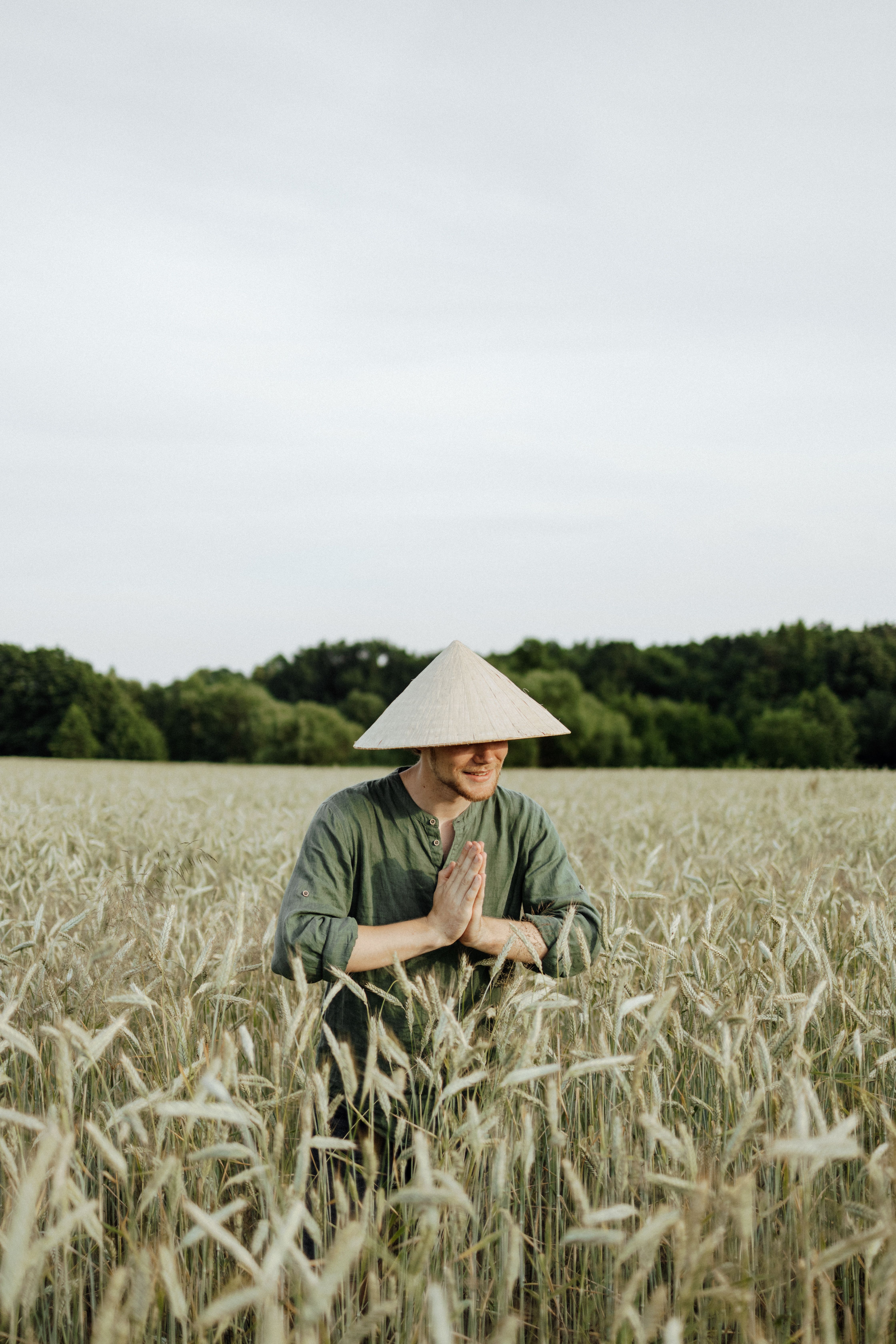 麦田里，一个男人头戴圆锥形帽子，双手紧握，神情宁静