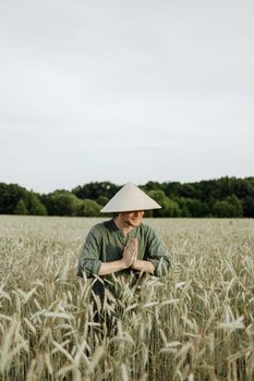 麦田里，一个男人头戴圆锥形帽子，双手紧握，神情宁静