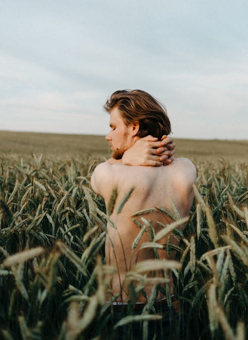 Shirtless Man Standing on Green Grass Field