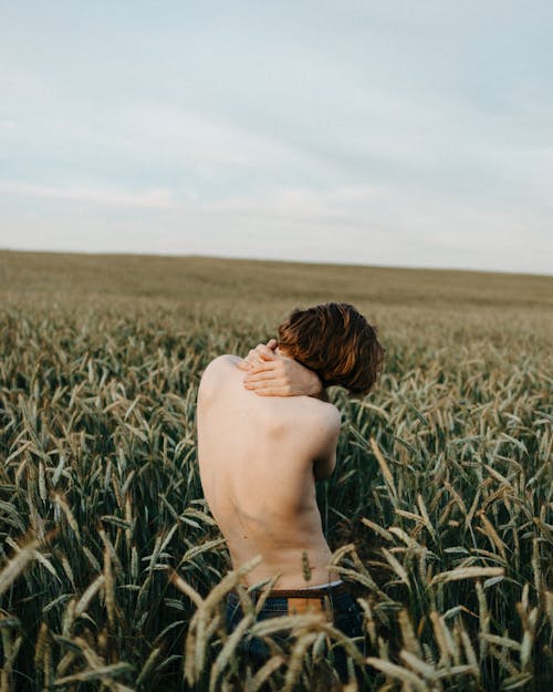 Topless Man in Black Bottoms Standing on Green Grass Field