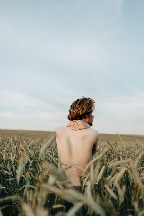 Shirtless Man Standing on Green Grass Field