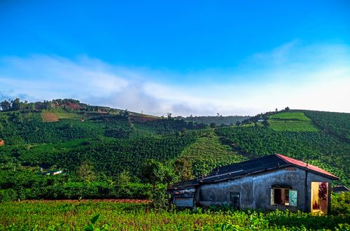 Free Vibrant rural landscape featuring a farmhouse amidst rolling green hills under a bright blue sky. Stock Photo