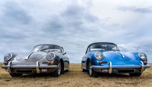 Free Two vintage classic cars showcased outdoors on a cloudy day, highlighting their timeless design. Stock Photo