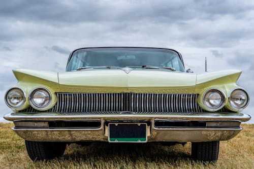 Classic Car on Green Grass Field Under White Clouds