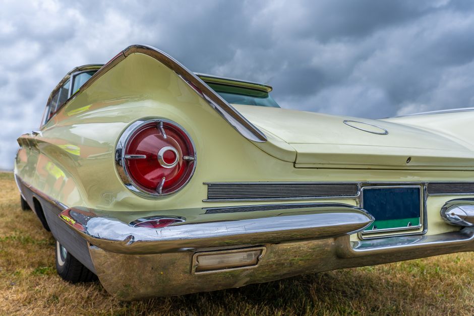 Rear view of classic vintage car with chrome finish under cloudy sky.