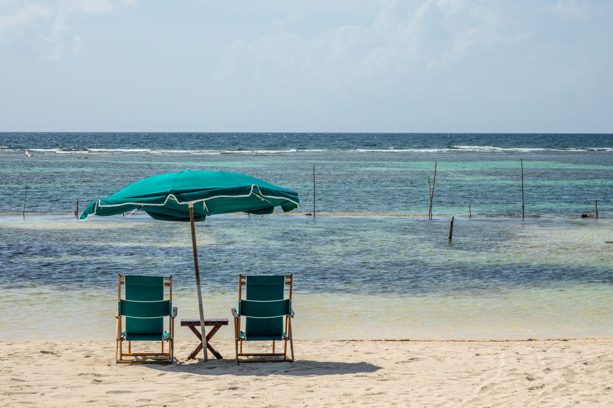 Beach chairs and umbrella facing calm ocean water