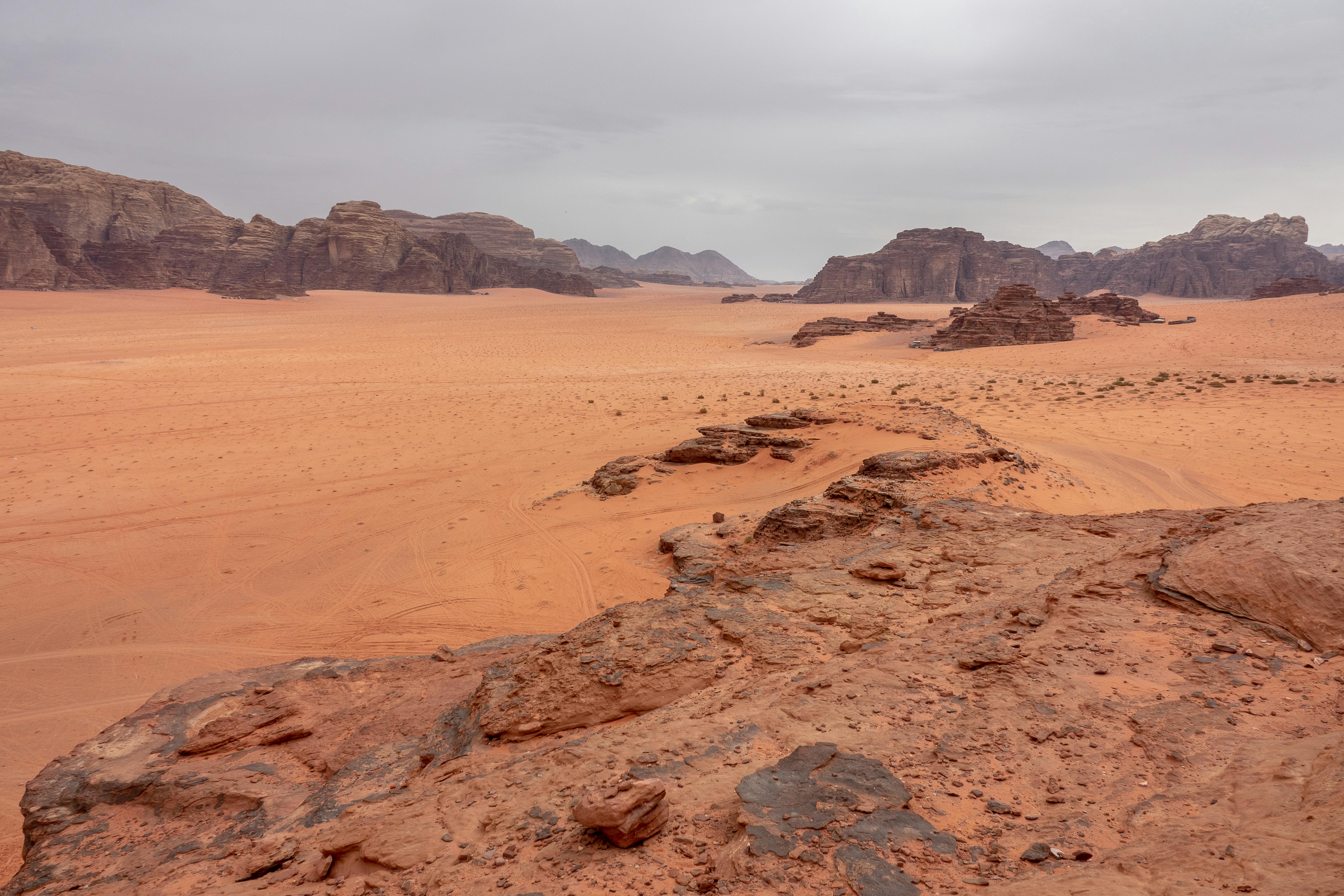 A Desert Near Rocky Mountains Under Gray Sky · Free Stock Photo