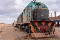 Blue and Red Train on Rail Tracks Under Cloudy Sky