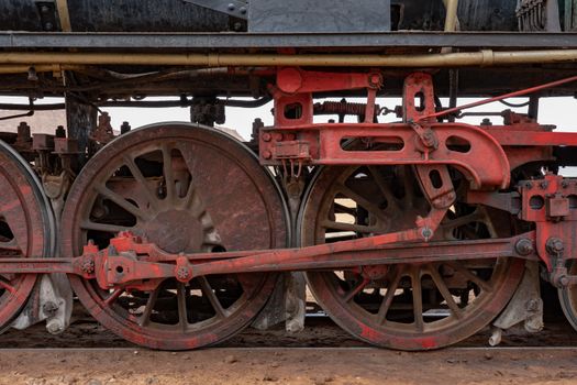 Detailed shot of large red vintage locomotive wheels showcasing intricate metalwork.