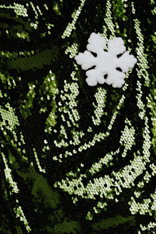 Free Close-up of green sequin fabric adorned with a white snowflake, creating a festive contrast. Stock Photo