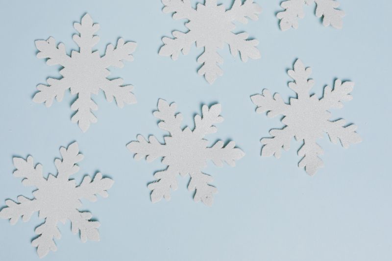 Delicate paper snowflakes arranged on a pale blue background