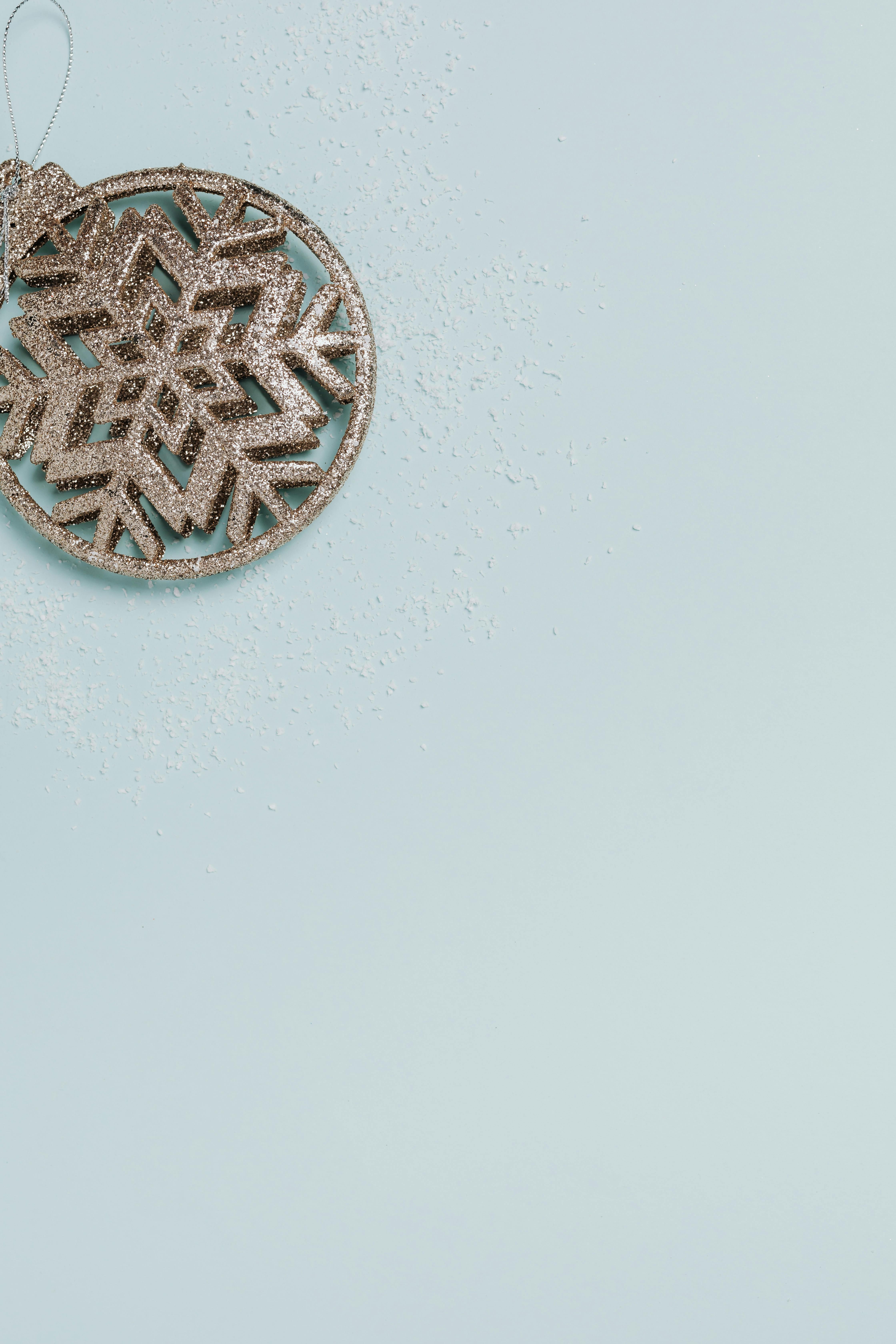 一个闪闪发光的雪花装饰品放置在点缀着闪光的蓝色背景上