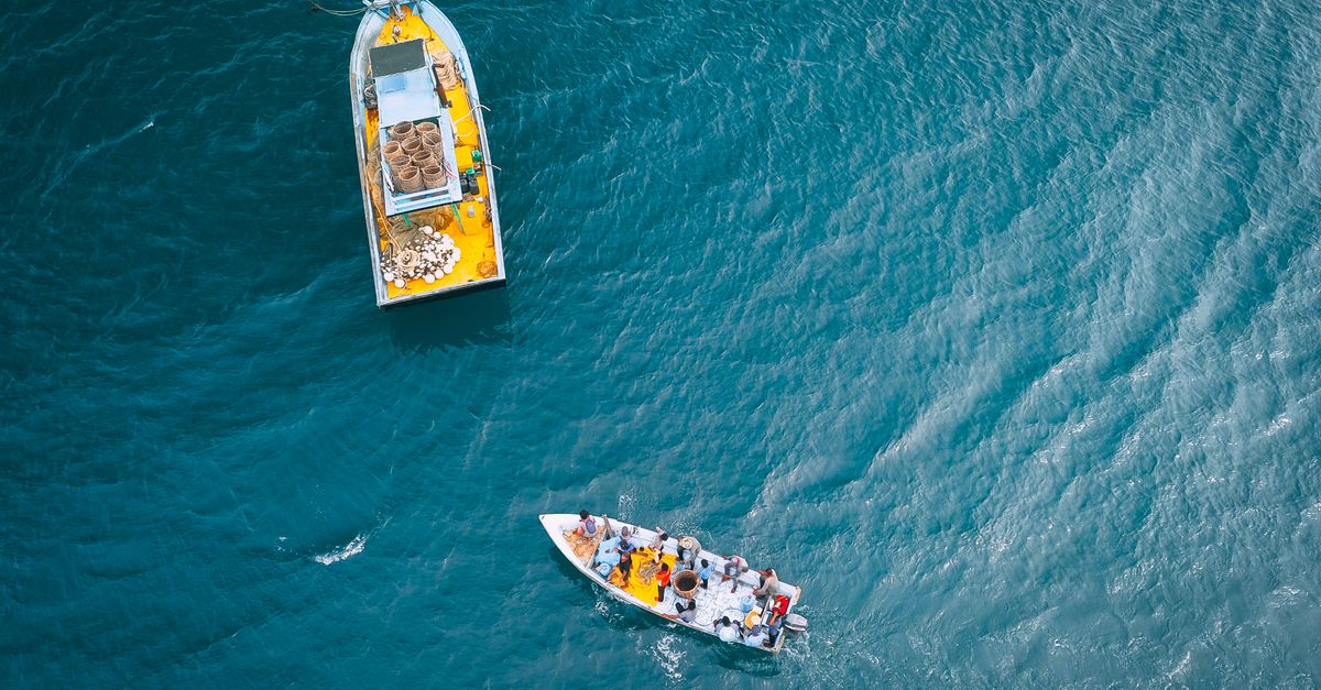 Photo by Pok Rie Top view of vessels with different equipment sailing in turquoise water of endless ocean