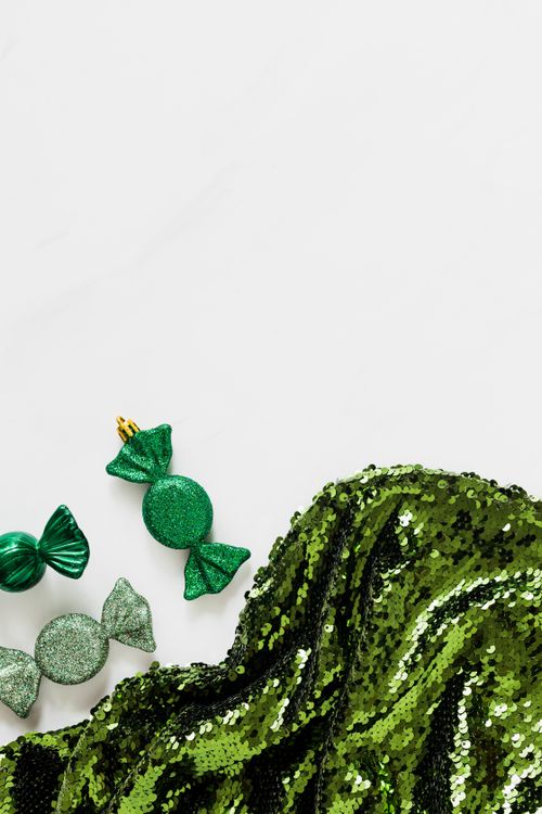 Free High angle view of green sequin fabric and candy-shaped ornaments on a white background. Stock Photo