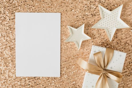Free A stylish flat lay of a wrapped gift and star-shaped decor on shimmering gold sequins, perfect for holiday themes. Stock Photo