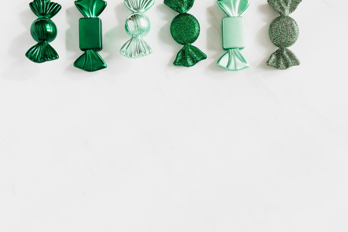 A collection of green wrapped candies arranged in a row on a white background.