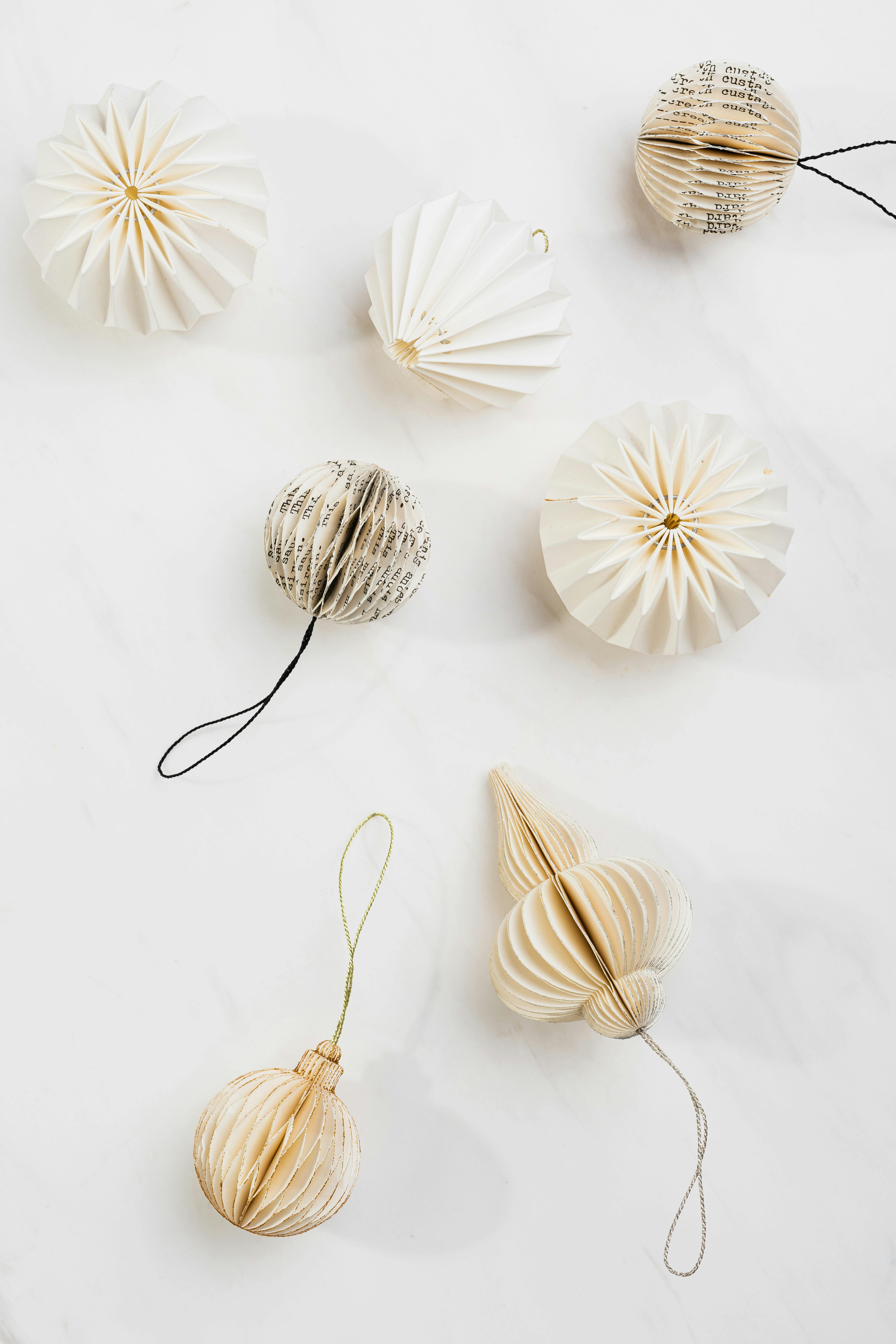 Minimalist flat lay of elegant paper ornaments against a white backdrop, perfect for festive themes.