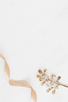 Minimalist image showcasing a golden twig paired with a ribbon on a white background, perfect for seasonal decoration.