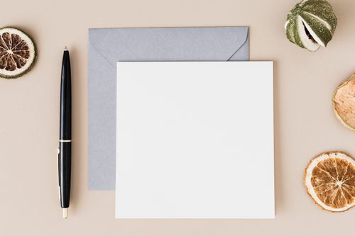 Free Top view of a minimalist flat lay featuring a blank paper, envelope, pen, and dried citrus slices. Stock Photo