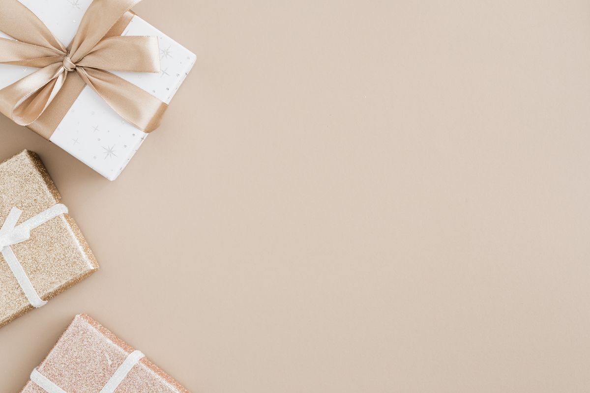 Neutral gift boxes with gold ribbon on a beige background.